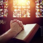 Praying hands on a Holy Bible